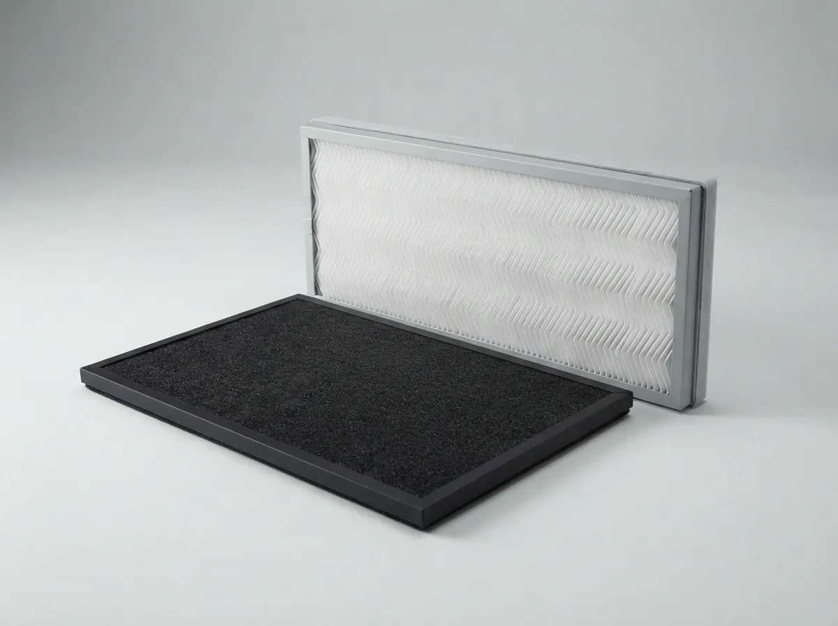 Black carbon filter layer and white pleated True HEPA filter panel arranged in a separated view on a grey studio surface