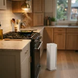 Air purifier running on a kitchen floor near a stove during evening cooking