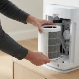 asset_00b41bd4af431ce3 Adult hands sliding a new Winix Filter Z canister into the open filter compartment of a Winix air purifier