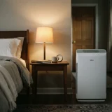 asset_041799d380c53fb9 Winix C610 air purifier beside a bedside table and lamp in a quiet bedroom