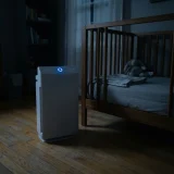 asset_07239af88998e618 Winix C610 air purifier glowing faintly beside a crib in a dark nursery at night