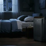 asset_108742acd6c180a5 Winix 9800 air purifier running beside a bed in a darkened bedroom at night