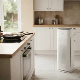 Winix Zero air purifier standing near a stove in a bright kitchen with steam rising