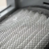 Macro close-up of the fine mesh pre-filter surface of a Winix Filter Z canister catching hair and lint