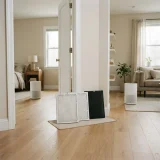 Two white pleated filters placed between a bedroom doorway and a living room with purifiers in each