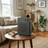 A Winix A230 air purifier on a side table in a living room with a cat tree blurred in the background