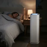 asset_2d2ed4a4eb9ee3d2 Winix C535 air purifier glowing softly beside a bed where one adult is sleeping