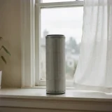 Tall filter cartridge on a windowsill with hazy outdoor air visible through the glass