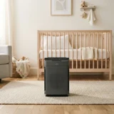 A Winix 5300-2 air purifier running in a softly lit nursery next to a crib