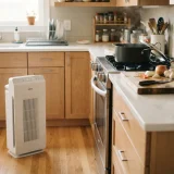 asset_4b7b0dae8e8e786e Winix C610 air purifier on a kitchen floor beside a counter with a pot and chopping board