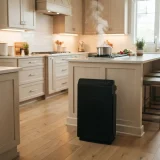 Winix 5510 air purifier standing on the kitchen floor a few feet from a counter with a steaming pot