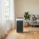 Winix 5520 air purifier standing beside a half-open window with sheer curtains