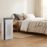 Winix 5520 air purifier running in a sunlit bedroom with light streaming across the floor