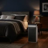 Winix 5520 air purifier running beside a bed in a dim bedroom at night