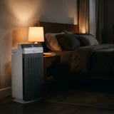 Winix 5520 air purifier running quietly beside a bed at night with a dim bedside lamp
