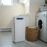 asset_80455a199939cbc8 Winix C535 air purifier running beside a laundry basket in a utility room