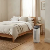 asset_85ff1c75c27a3968 Winix D480 air purifier running on the floor of a made-up master bedroom in soft morning light