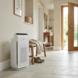 Winix Zero air purifier beside a hallway bench where pollen season coats a jacket and shoes