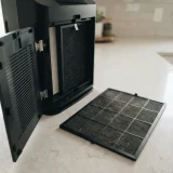 Winix 5510 rear filter door open with the fine mesh prefilter panel lifted out and resting on a counter