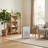 A Winix C610 air purifier running in a bright living room near shelves and a plant