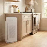 asset_a0f840c5cc485876 Winix C535 air purifier on a kitchen counter edge while a simmering pot releases steam on the stove
