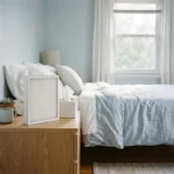 asset_a9ef56e1549a74a9 White pleated filter on a bedroom nightstand with a tissue box and morning light on the bed