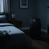 Winix 5510 air purifier running in a dim bedroom at night with a low glow from its indicator