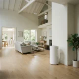 A large air purifier running in a spacious family room with a high ceiling and open doorway