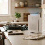 A Winix C610 air purifier operating on a kitchen counter after cooking, with steam and pans nearby