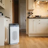 Winix 5520 air purifier on a kitchen floor near a stove with a pan cooking