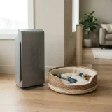 A Winix air purifier on a living-room floor beside a woven dog bed with scattered pet toys