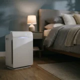 asset_fc9e91494f0faa26 Winix C545 air purifier beside a made bed in a dim bedroom at night